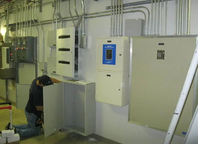 Technician inside an I/O building working at a row of motor control center cabinets.